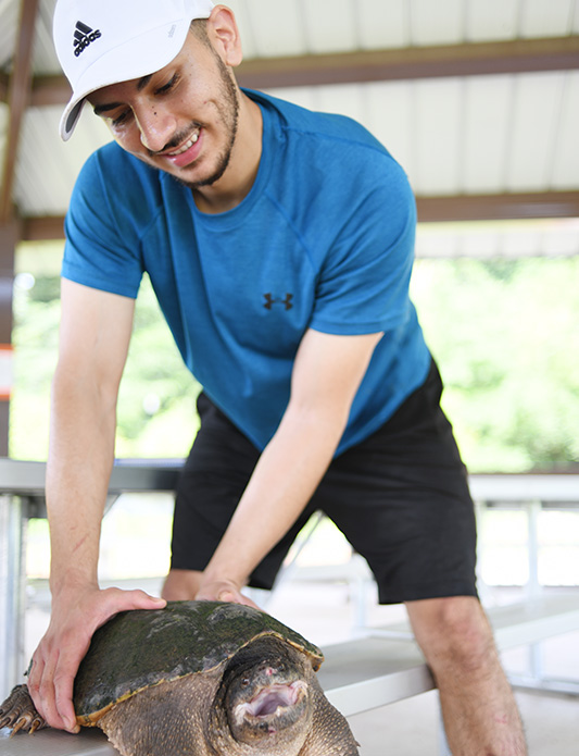 student holding down a snapper turtle