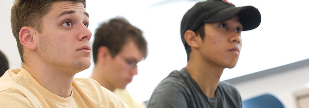 two students sitting at desk looking forward at front of classroom